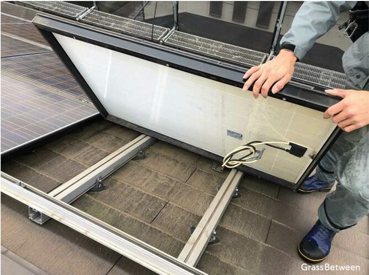 屋根葺き替えのため太陽光パネルを外す作業員画像
